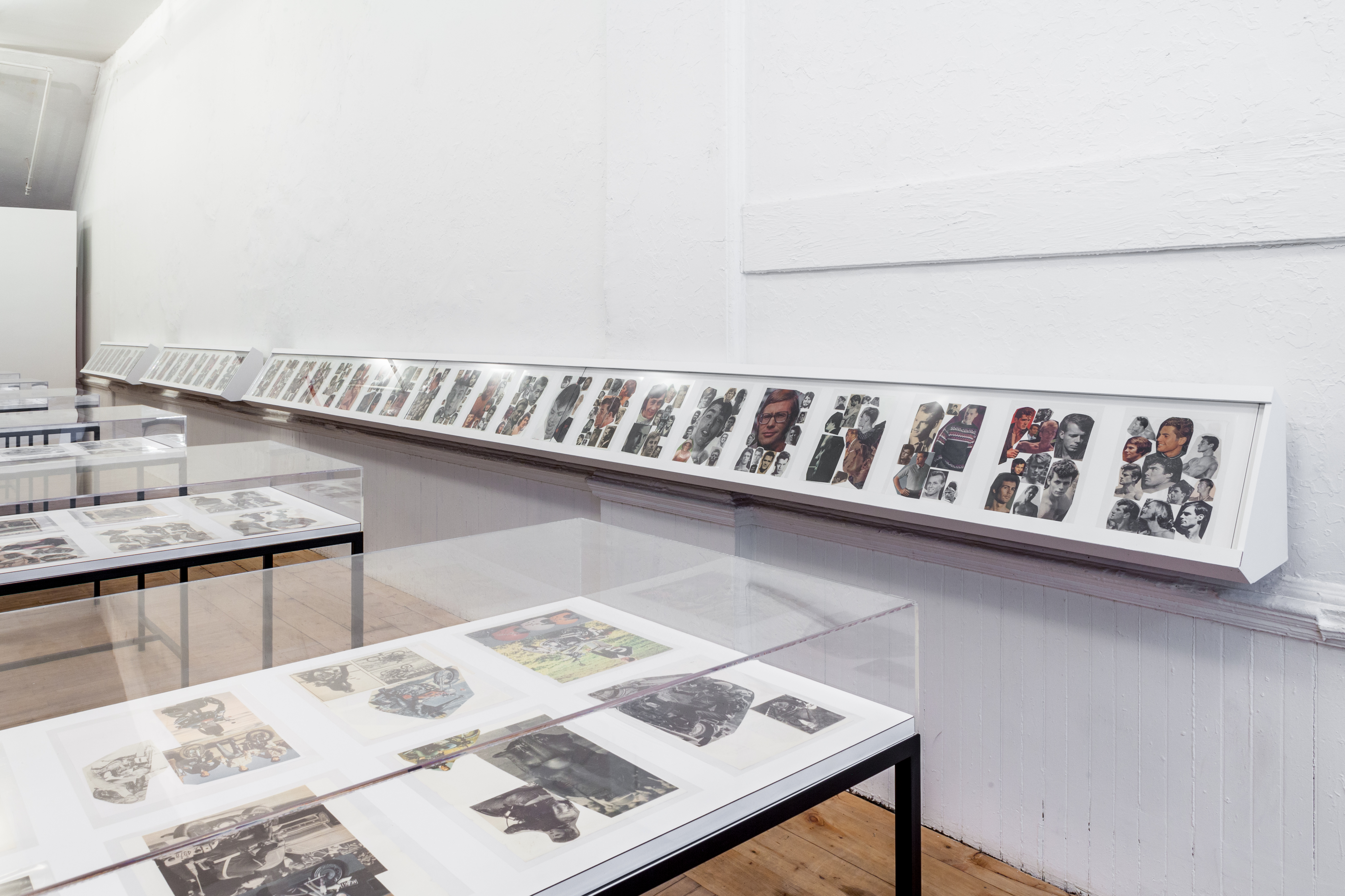 An angled view of vitrines and book cases displaying collages.