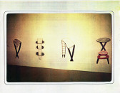 Painted objects attached to the wall in a white-walled gallery space.