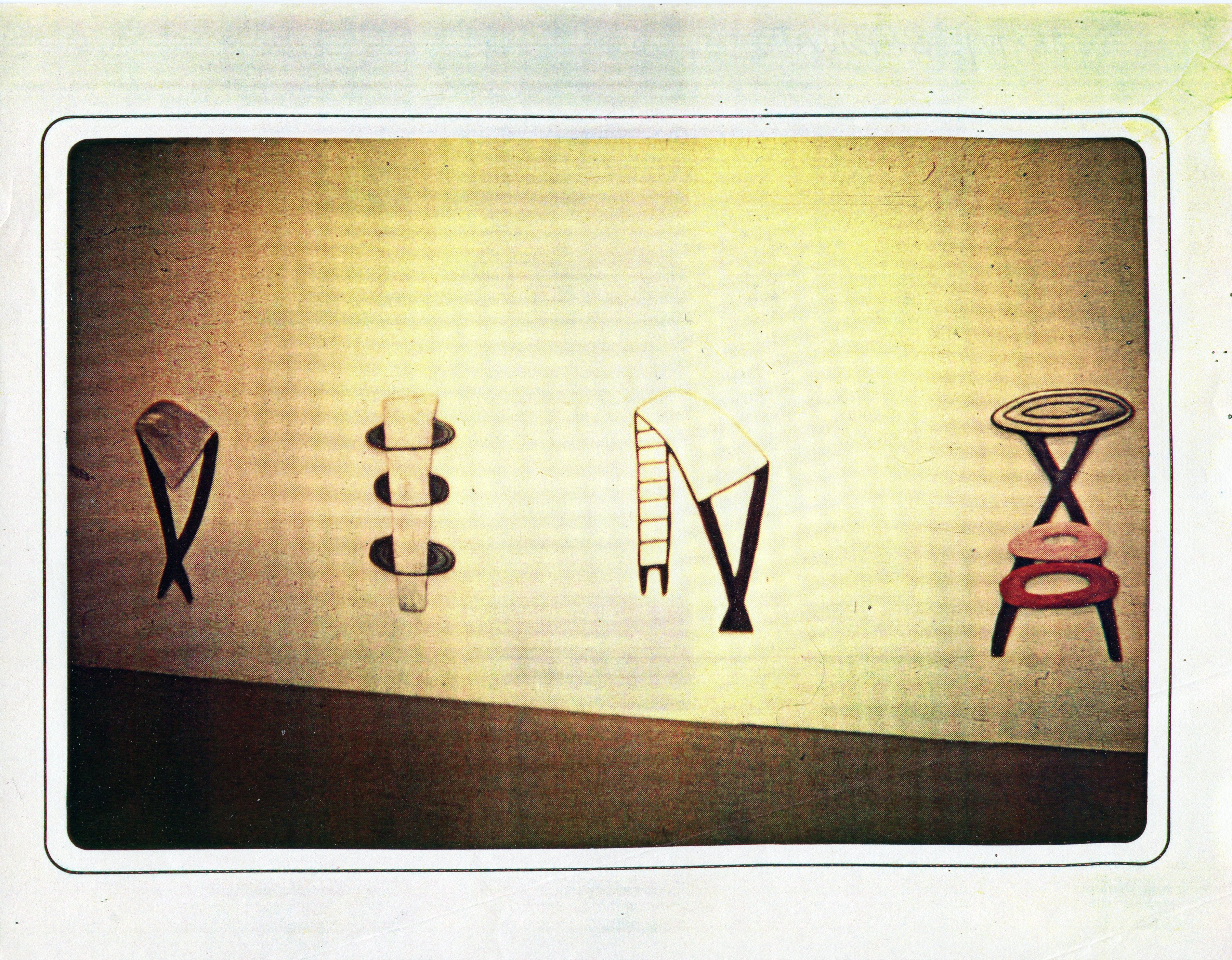 Painted objects attached to the wall in a white-walled gallery space.