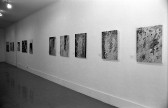A row of square paintings hangs on a wall.