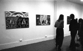Various paintings hang on the walls as guests enjoy the exhibition opening.