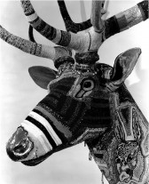 A close up detail of the sculpted deer head with patterned designs on its face and antlers.