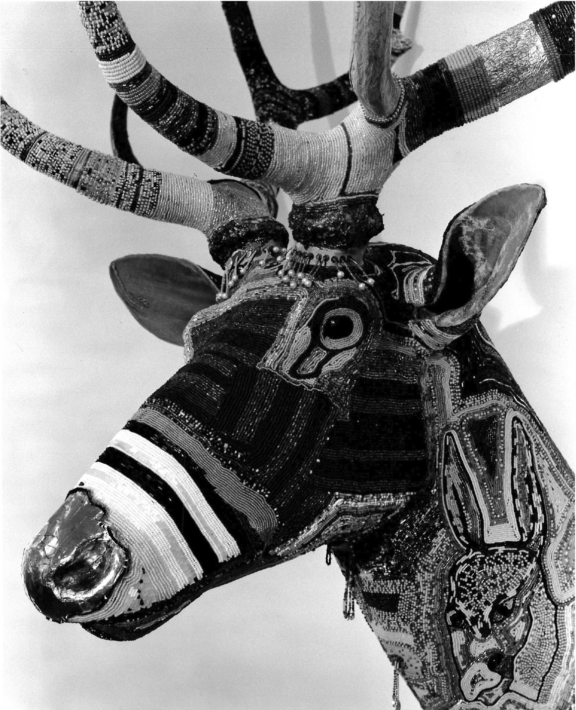 A close up detail of the sculpted deer head with patterned designs on its face and antlers.