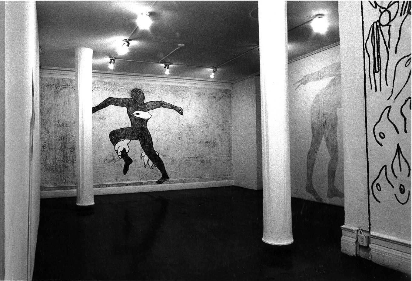 Multi-wall drawing of various figures visible in gallery space.