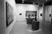 Paintins appear on white gallery walls with two sculptures on pedestals on the gallery floor.
