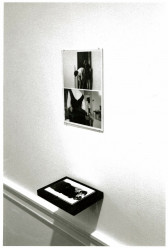 Photographs hanging on a wall above a photograph on a wall shelf.