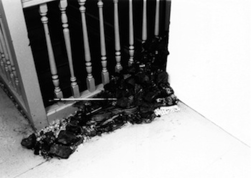 A pile of dark earth and plant matter is heaped against a wooden bannister.