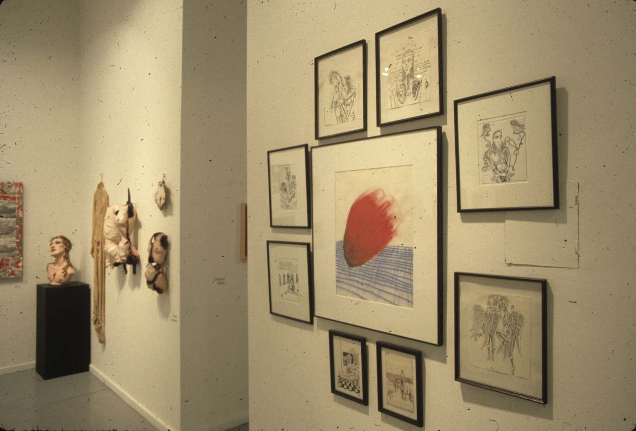 Various paintings, drawings, and sculptures of torsos hang along a wall.  In the corner, a bust with an upturned face sits on a pedestal.