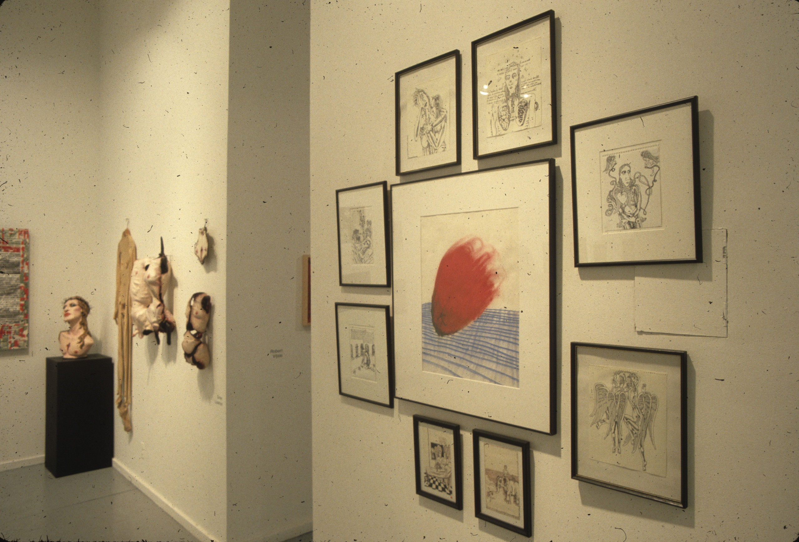 Various paintings, drawings, and sculptures of torsos hang along a wall.  In the corner, a bust with an upturned face sits on a pedestal.