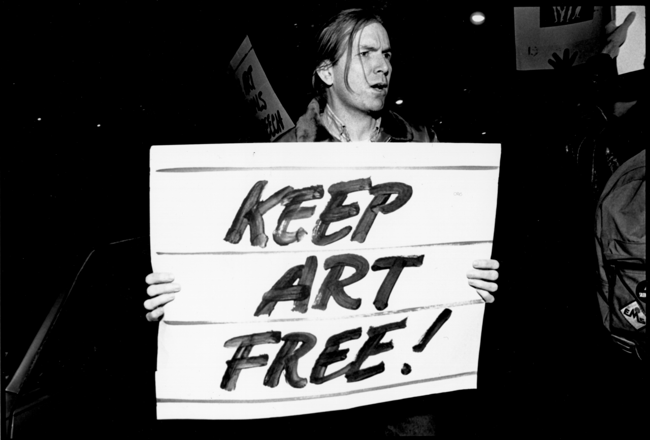 A person holds a sign that reads 