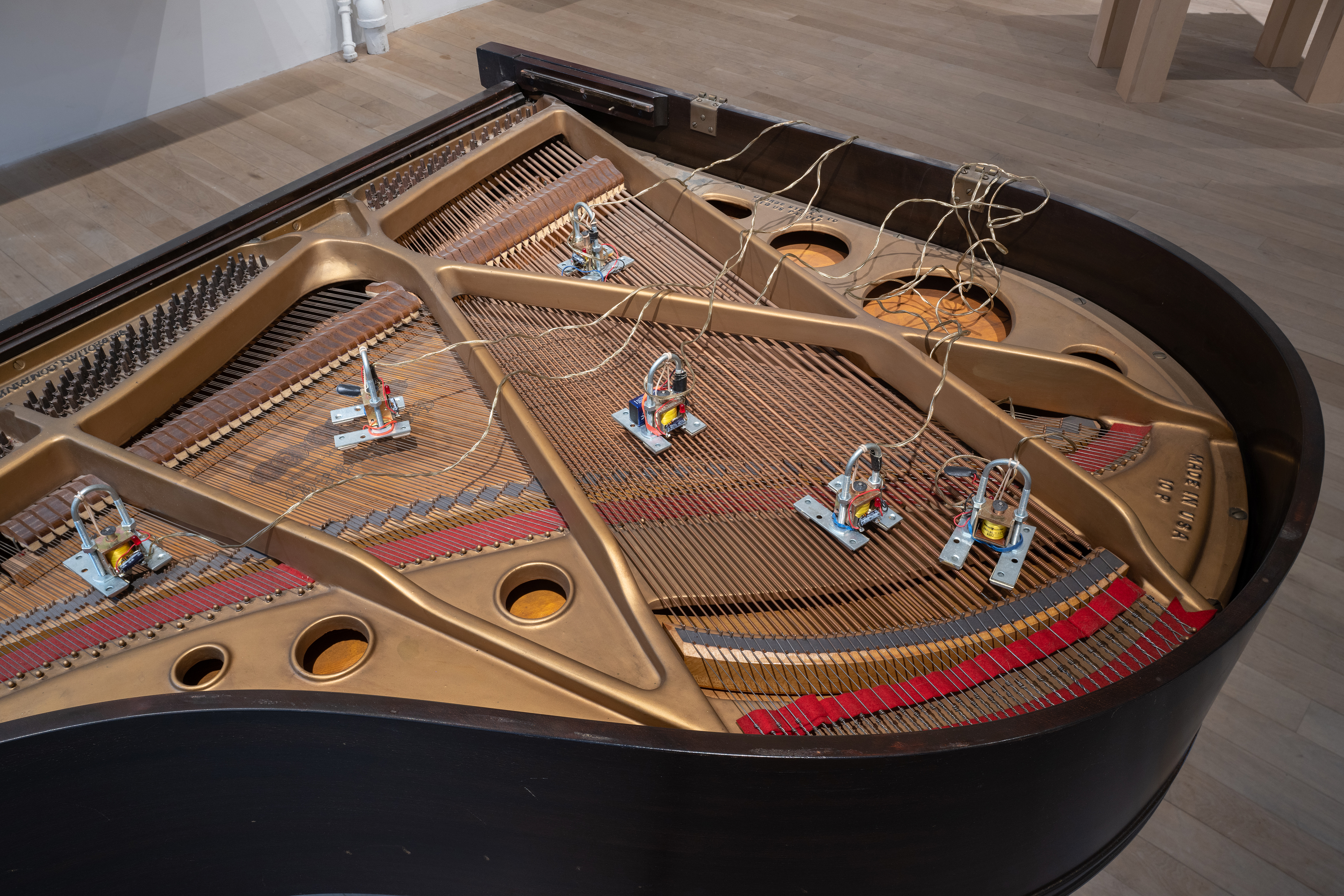 Color photograph of a piano. Six solenoids are placed along the piano's strings.