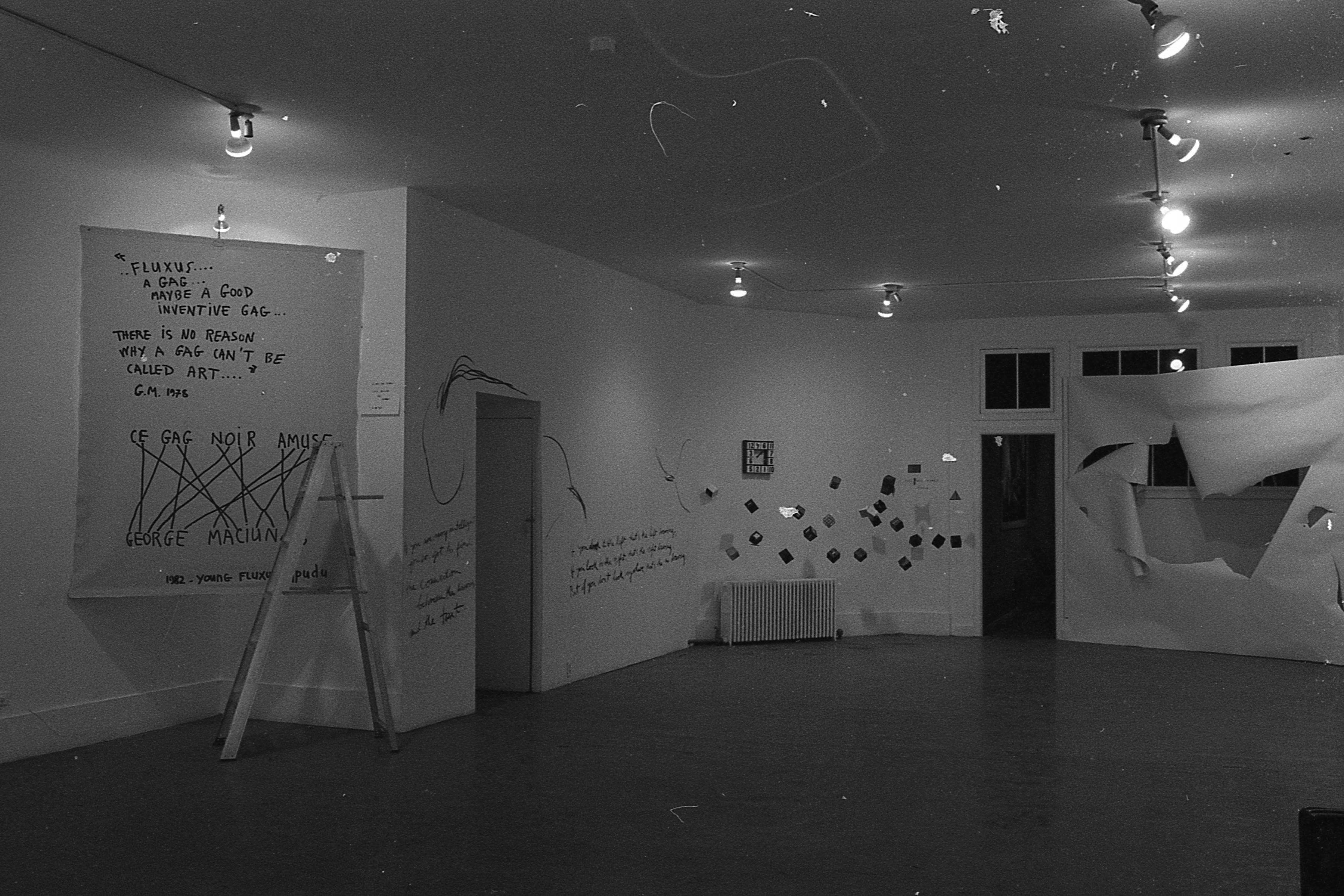 Numerous artworks appear on the walls of a white-walled gallery space.