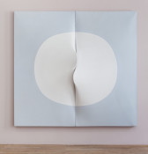 Two light blue panels of canvas displayed on a light mauve wall. The canvases are positioned side-by-side such that they form a square shape. Two semicircles are depicted on each of the canvases, which together form a white circle in the center of the two canvases. At the center of the circle, the edges of each of the canvases stretch outward to form two protruding flaps that curve towards and on top of the opposite canvases.