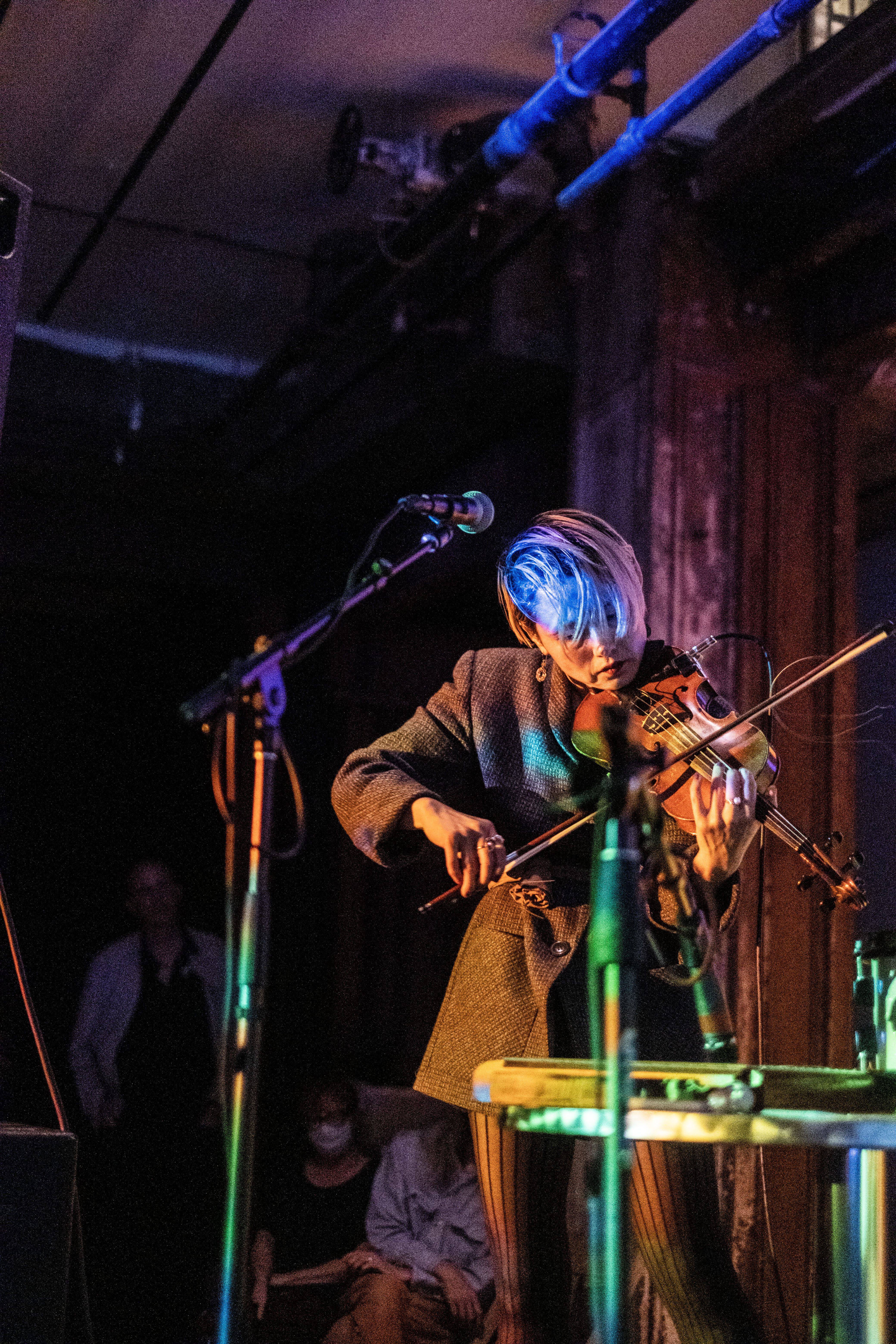 A figure plays the violin in front of a microphone.