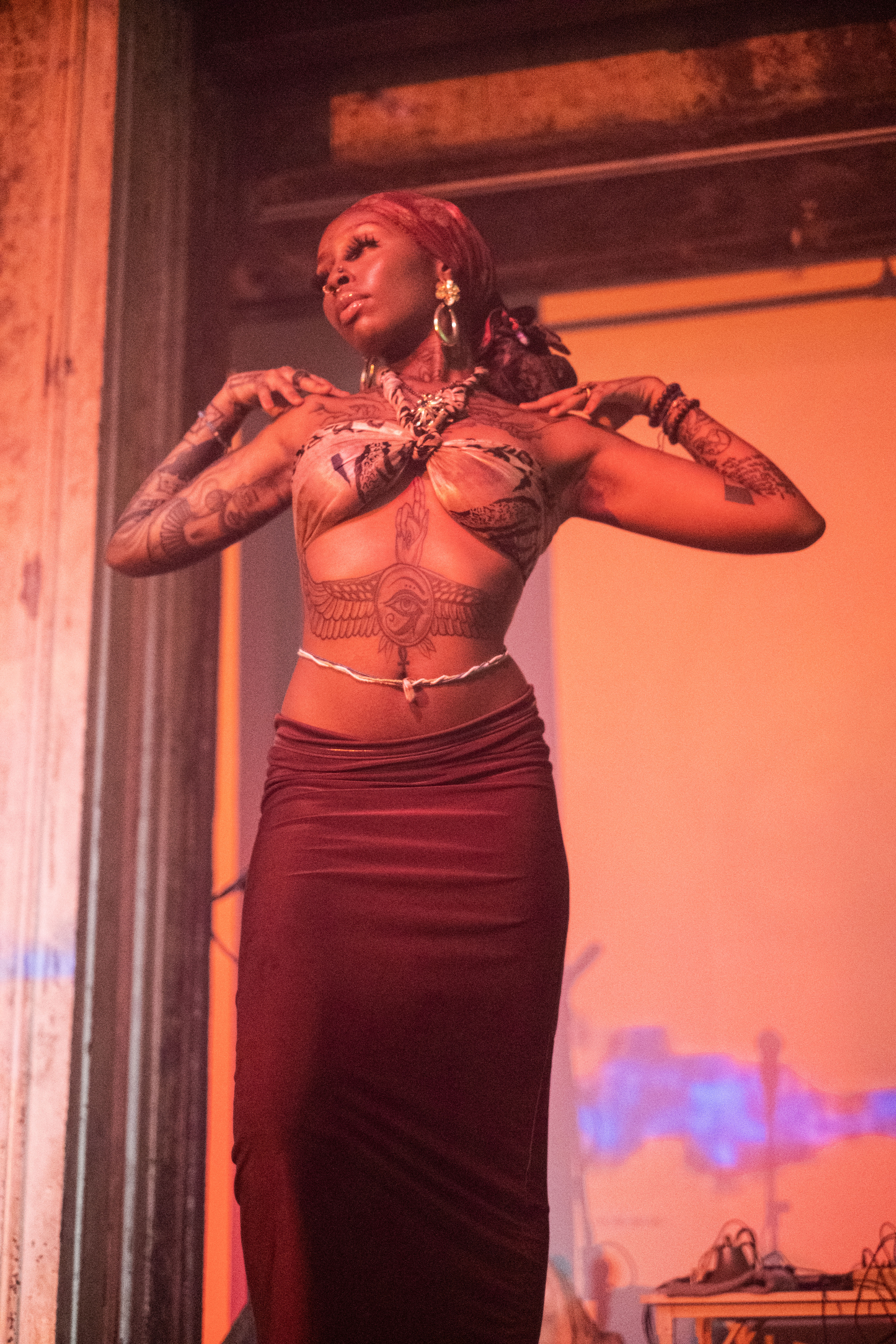 A figure dances on stage against an orange and blue projection.