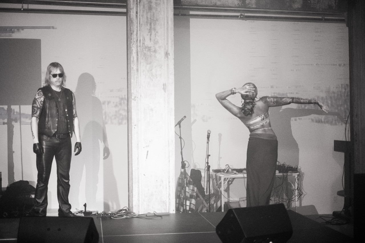 Two figures dance on stage in black-and-white.