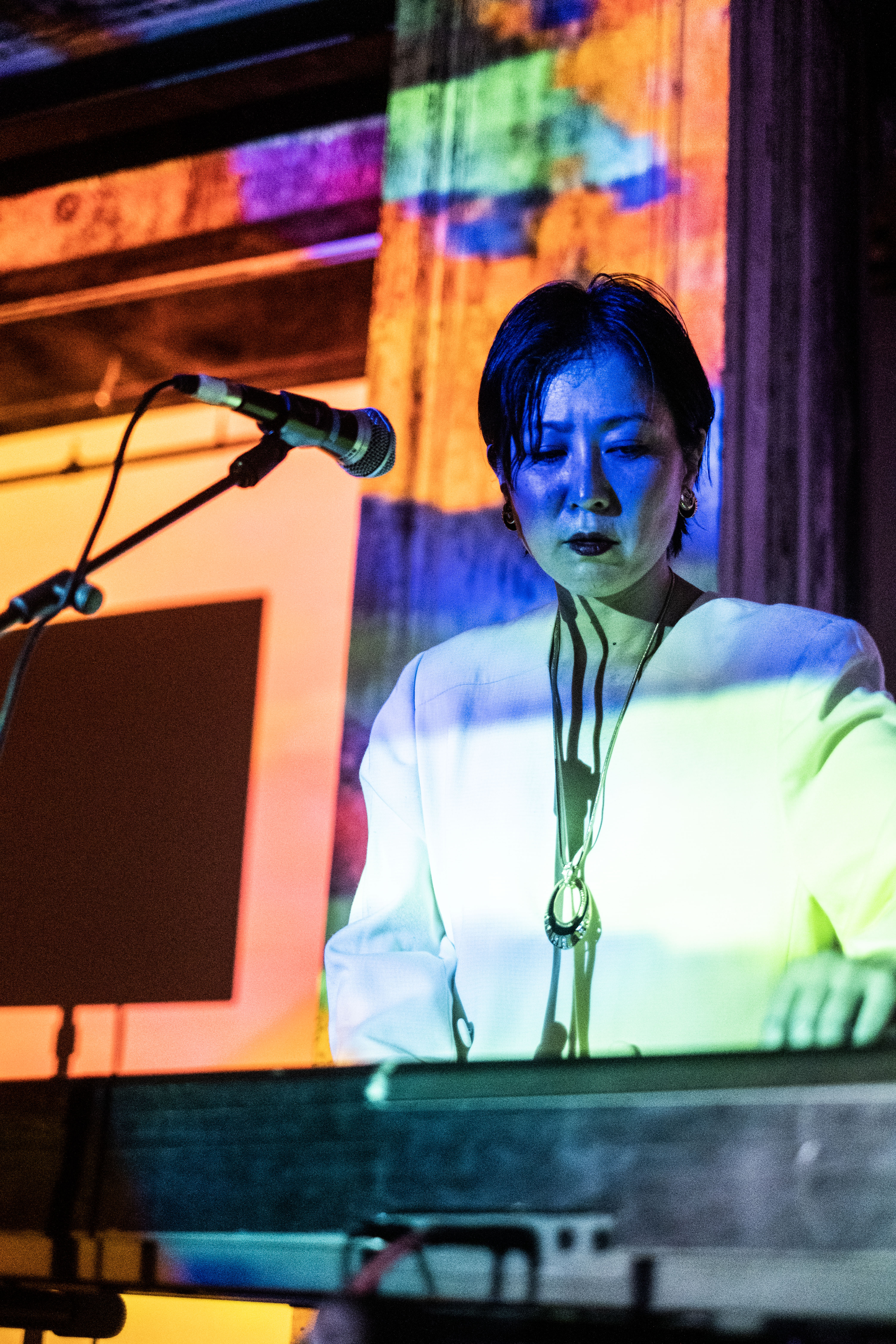 A figure plays the keyboard in front of a microphone.