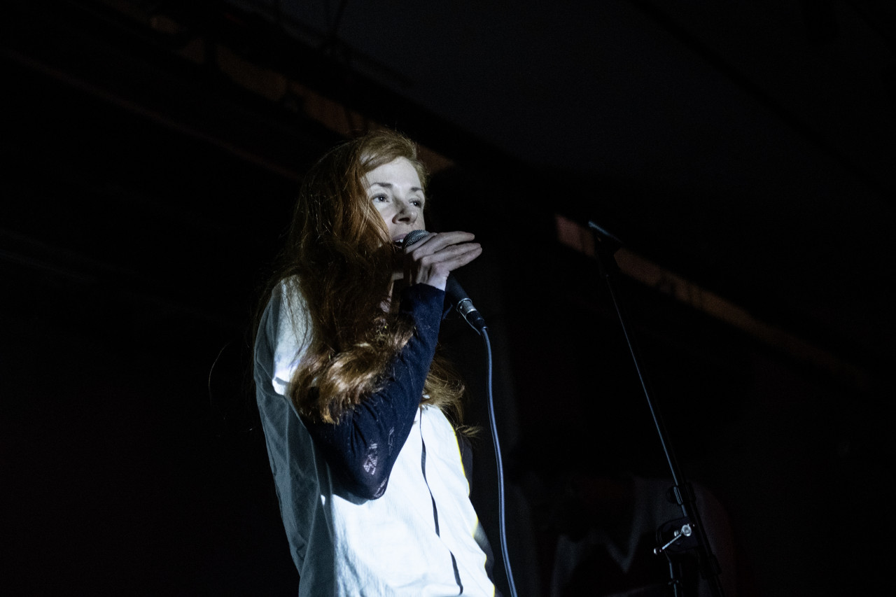 An illuminated performer sings into a microphone.