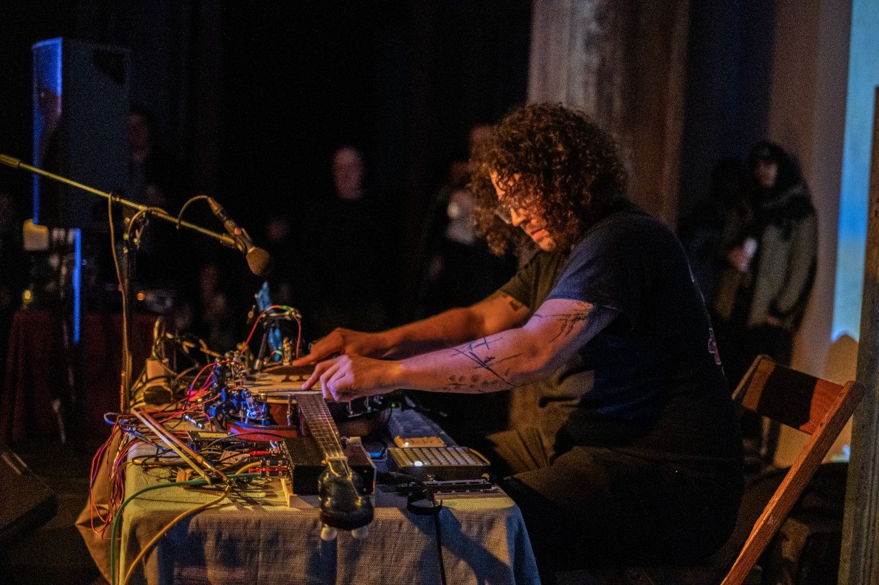 A performer plays a modified string instrument on stage.