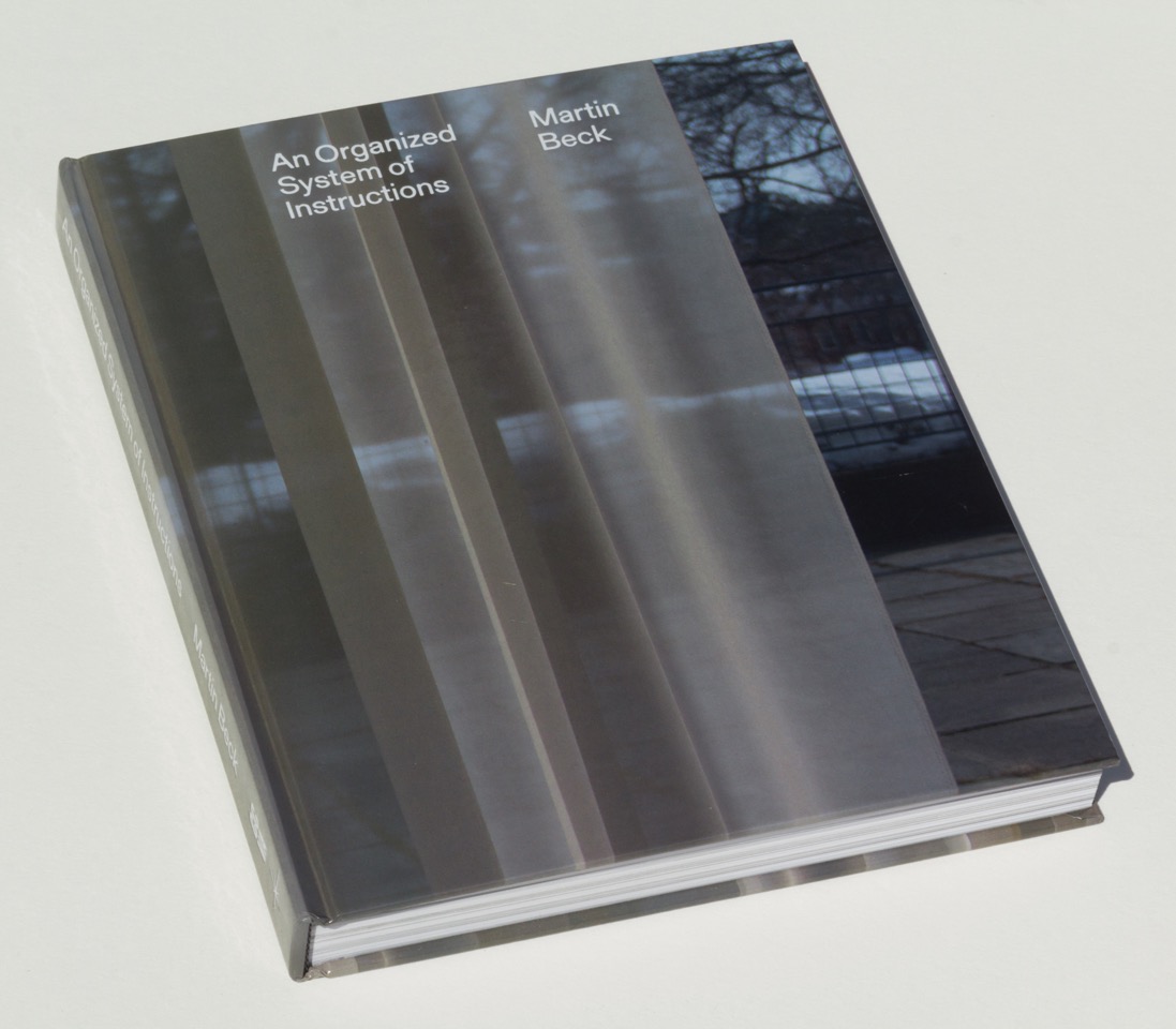 A hardcover book depicting a blueish outdoor park obscured by several grey sheets.