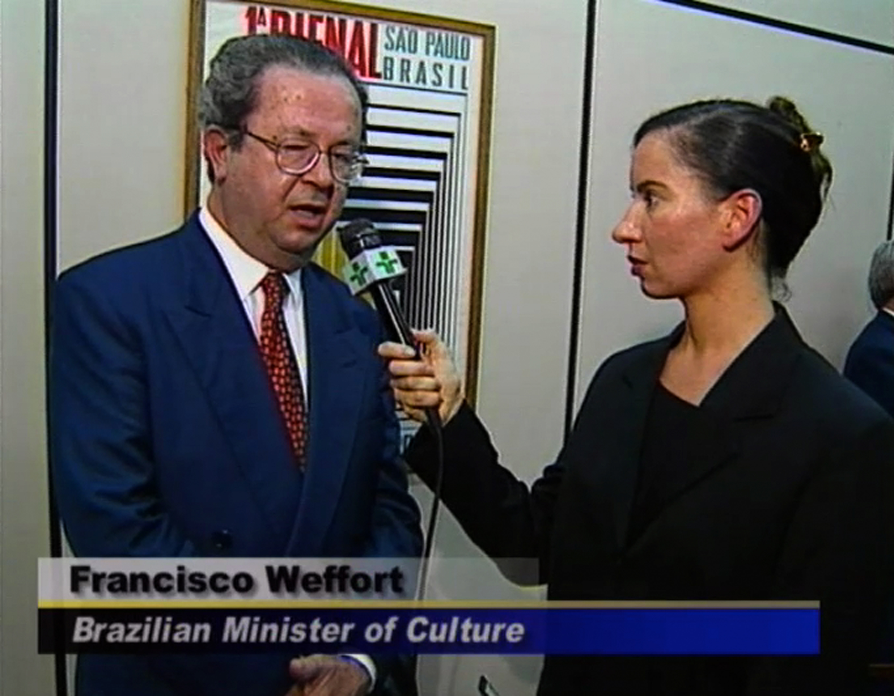 A woman interviews Francisco Weffort, the Brazilian Minister of culture, holding out a TV microphone.