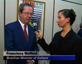 A woman interviews Francisco Weffort, the Brazilian Minister of culture, holding out a TV microphone.