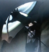 Photo of a woman partially obscured by a white umbrella. A light shining on the umbrella casts a large shadow of the woman's hand on its curved surface.