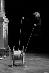 Black-and-white photo of a person pulling two ends of a rolled-up rope