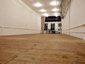 A low-angled view of an empty gallery space with wooden flooring and white walls.
