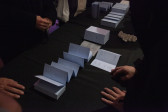 A row of small folded blue books are displayed on a black table. A piece of white coral is also placed in the middle of the table.