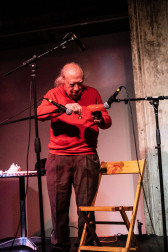 A figure plays a bell into three microphones.