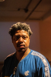 Portrait of a figure in a blue shirt looking into the camera.