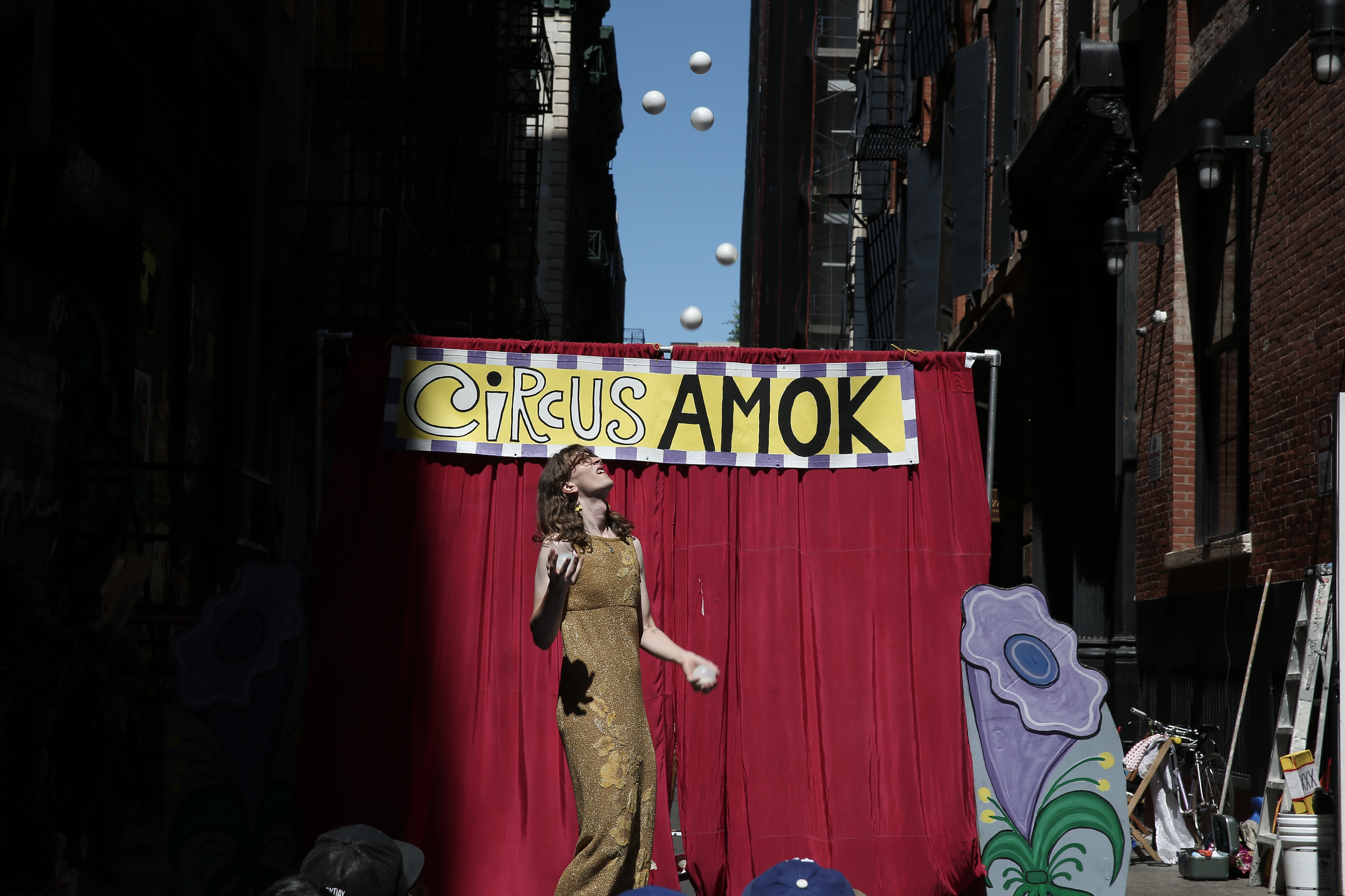 A figure stands in the center of the image, juggling several small white balls above their head.