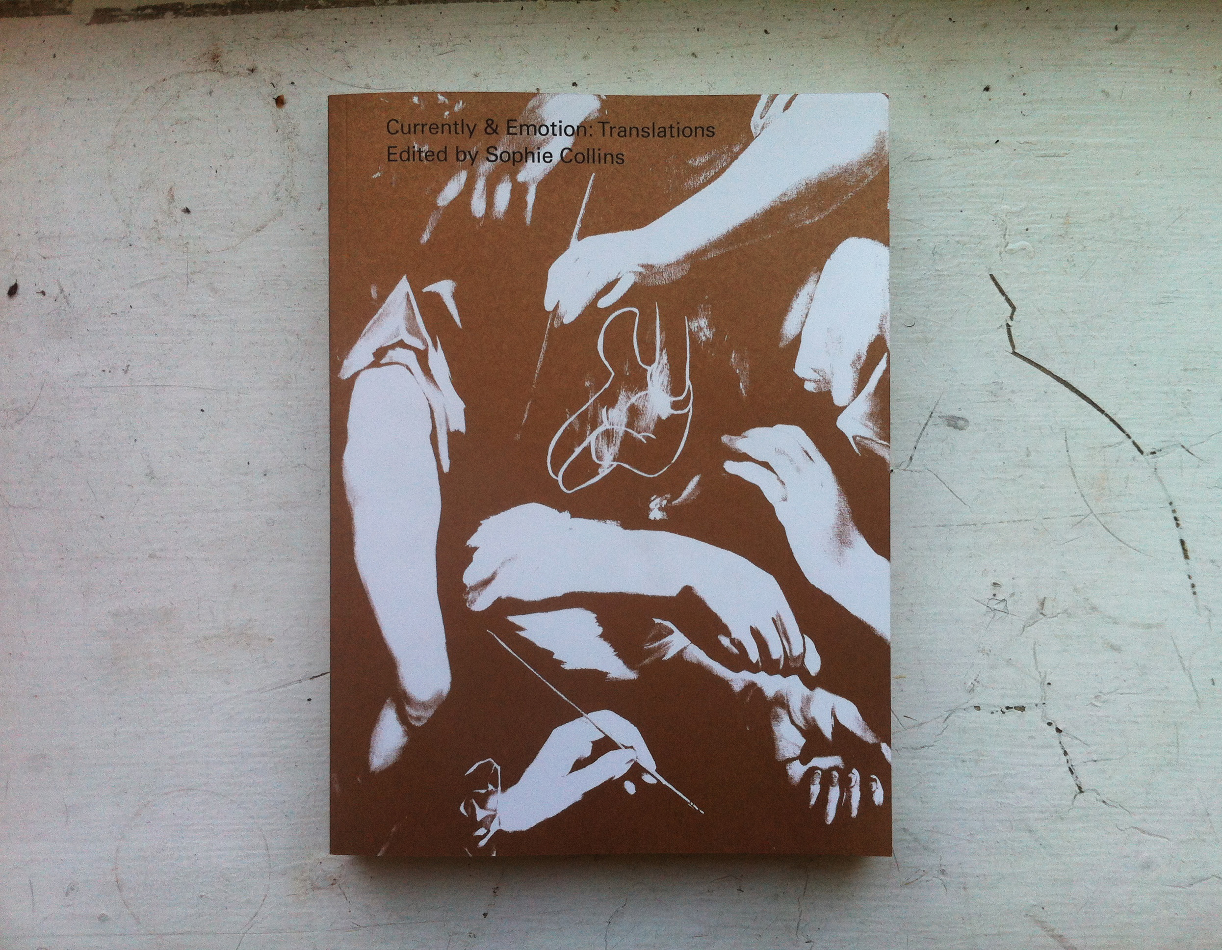 A brown and white book cover depicting several forearms and hands wrapped around each other against a dark background.
