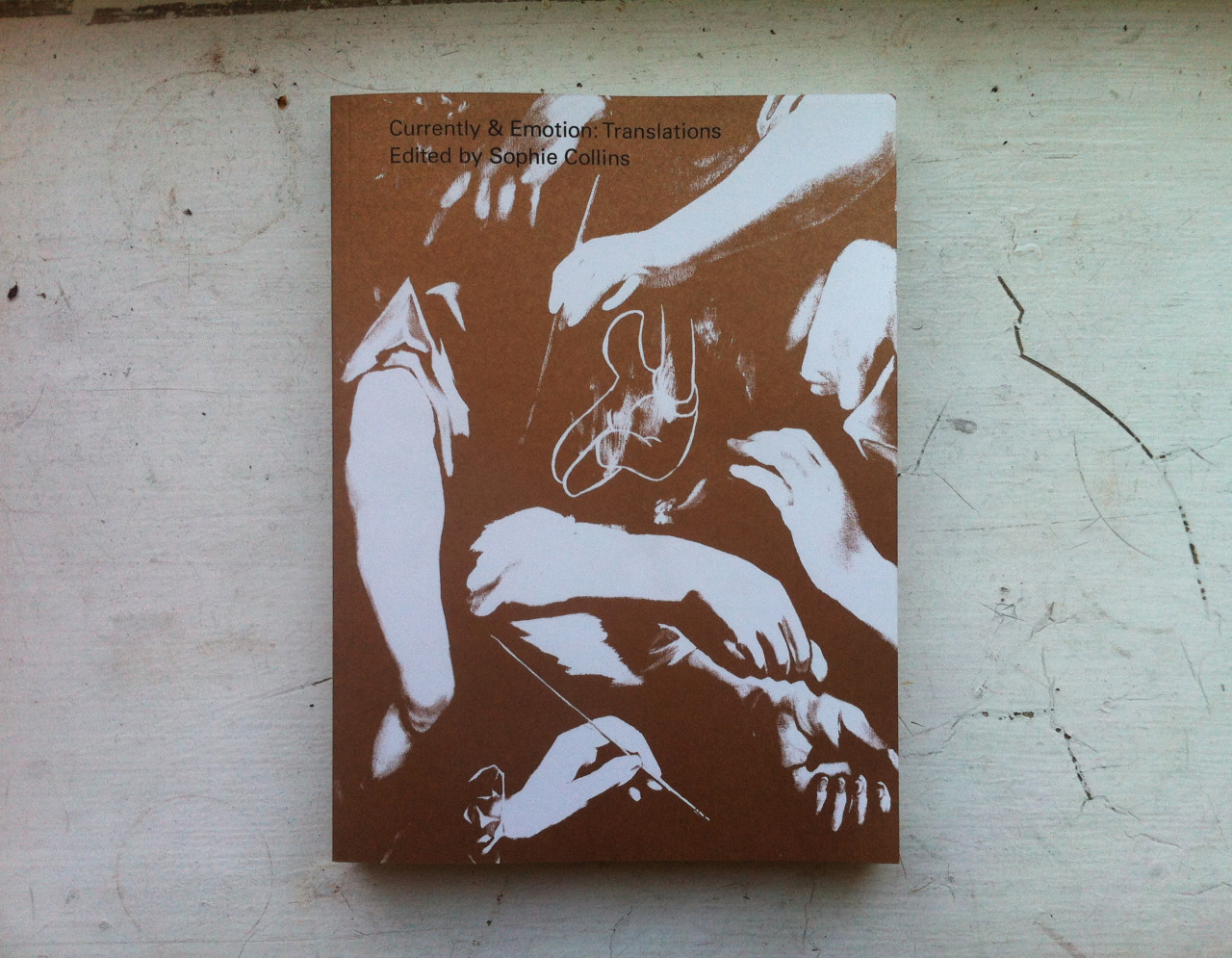 A brown and white book cover depicting several forearms and hands wrapped around each other against a dark background.
