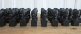 Black busts of Vladimir Lenin arranged in a grid formation on a table.