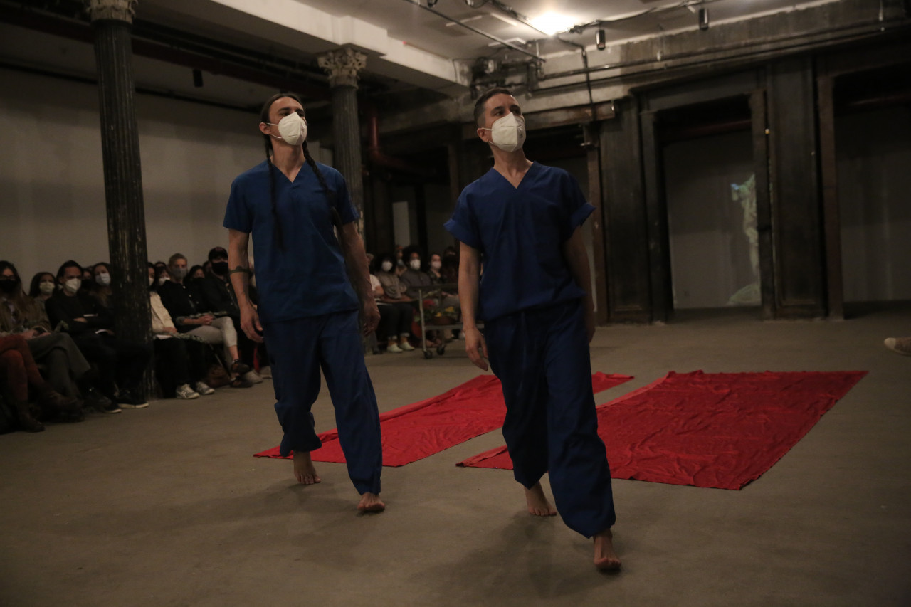 Two figures wearing medical scrubs gaze into the distance.