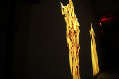 A projection of elongated, yellow-gold figures.