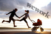 A man and woman hold hands while running, captured as though suspended above the ground. The woman pushes a red baby stroller in front of her. The scene is backlit, with the sun over a body of water behind them. On the upper right hand corner is the logo for 