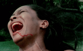 A woman screams as a trail of blood runs down her chin.