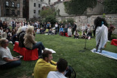 A stone-walled lawn filled with people watching Kembra Pfahler.