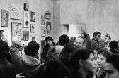 A black and white photograph of a crowded room filled with people conversing.