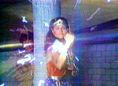 VHS-distorted image of Wonder Woman holding up her fist, from which emanates a burst of energy.