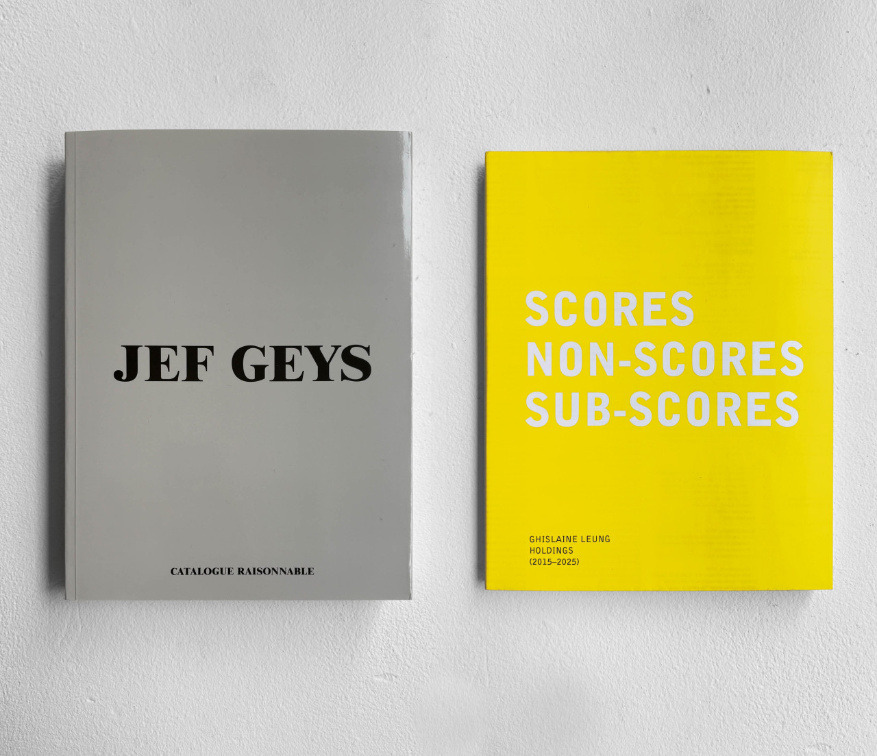 Two books lay side by side. On the left, a gray cover with black text reads "JEF GEYS." On the right, a yellow cover with white text reads "SCORE / NON-SCORES / SUB-SCORES."