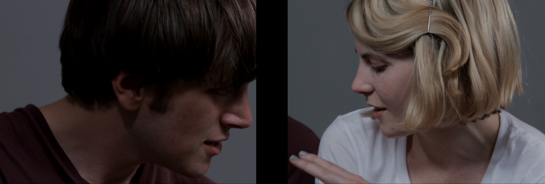 A man and a woman in a split screen view with a black space between them. The man's face is turned to the side; the woman is facing towards him, her eyes cast downwards, with two fingers pointing.