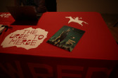 A table covered with a red tablecloth. The tablecloth is decorated with two white images: a person riding a horse and stylized text reading 