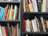 A close-up photo of a variety of books standing across several metal shelves.