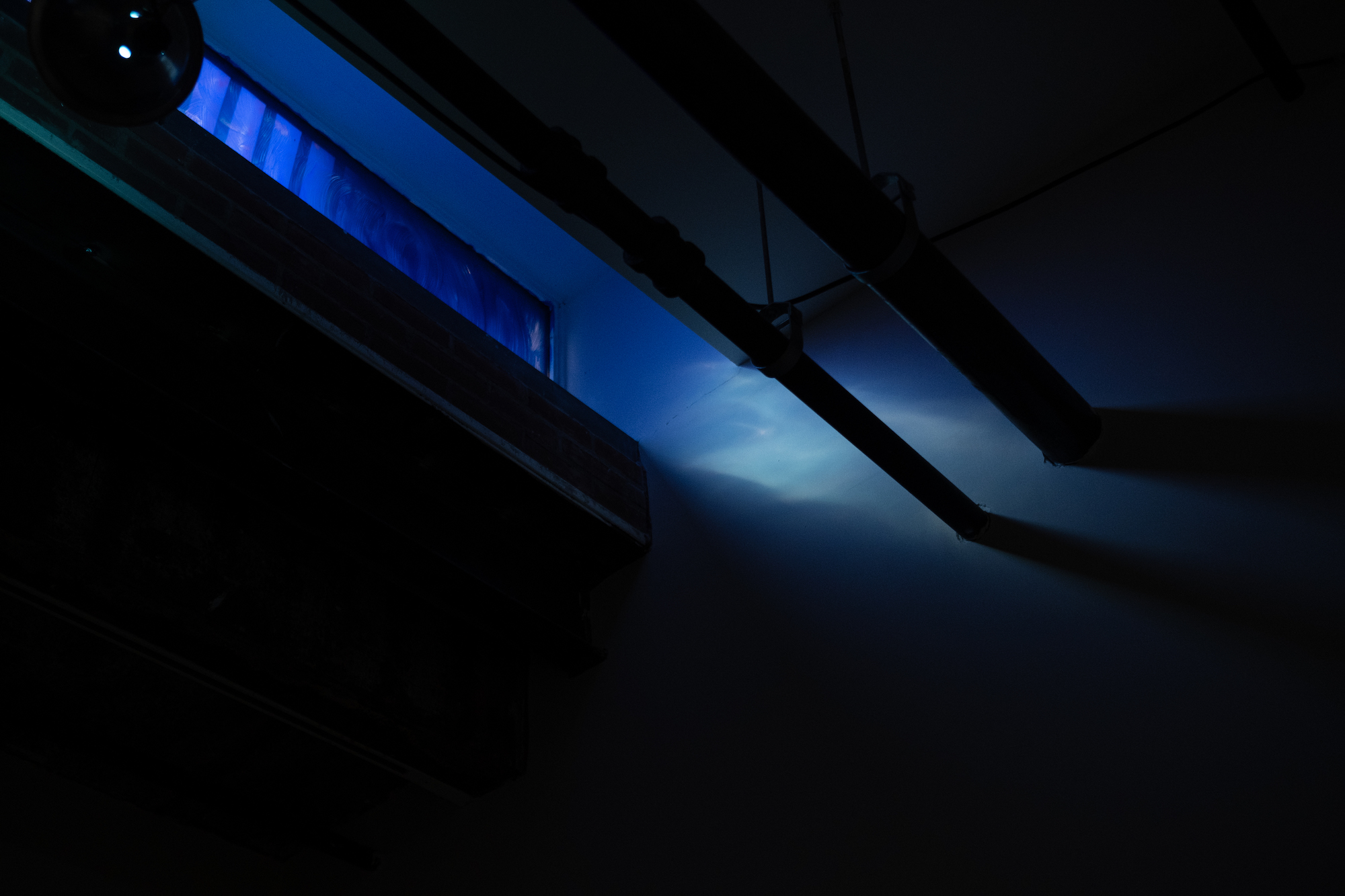 Image of a basement window that has been tinted with blue paint, streaming in blue light.