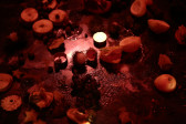 Half-eaten fruit, chocolate, and candles sit on a low, stone tabletop under dim lighting.