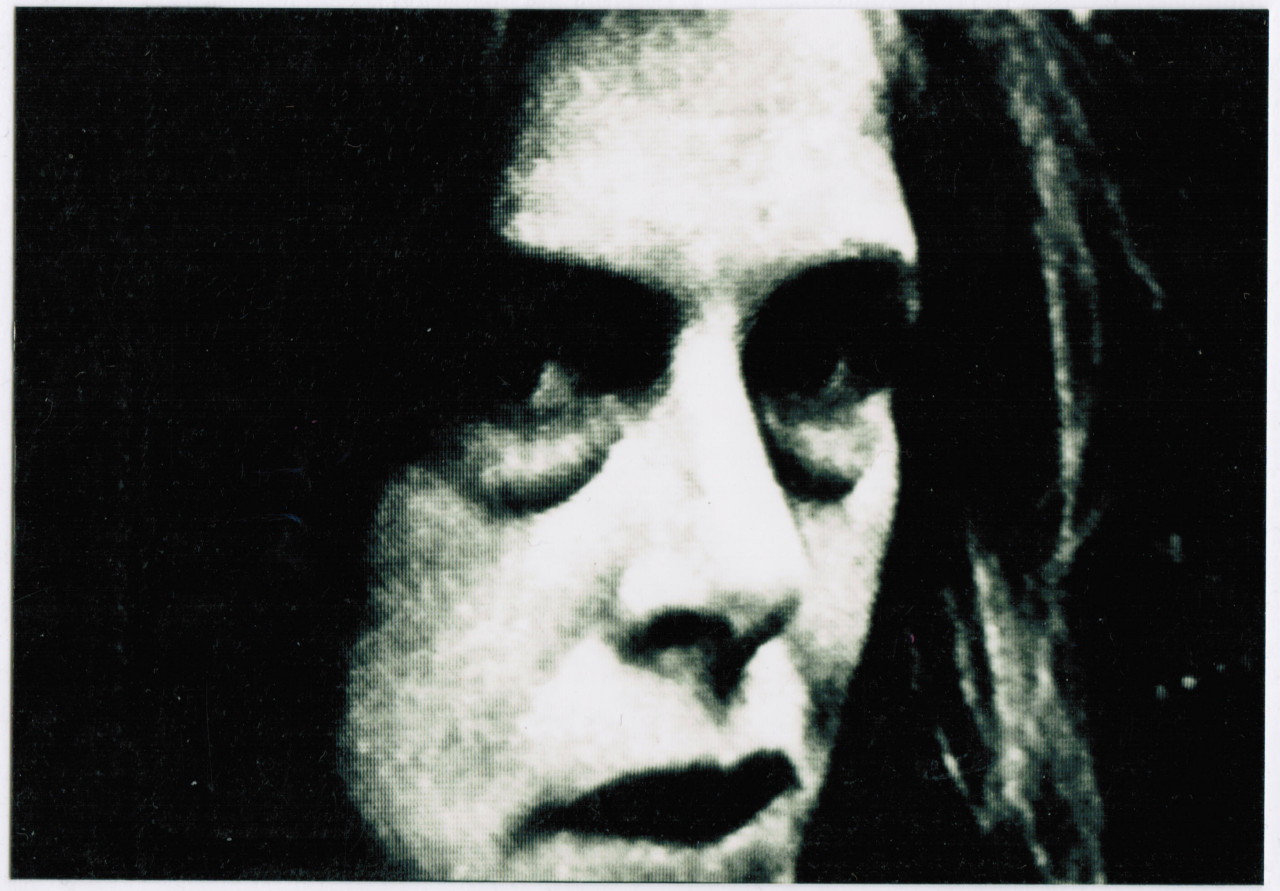 A grainy, black and white close up of a person, their face partially in shadow.